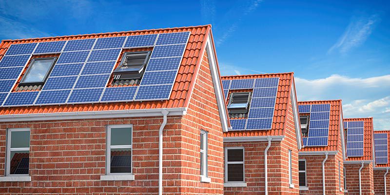 row-of-house-with-solar-panels-on-roof-on-blue-sk-2021-08-26-16-56-56-utc row-of-house-with-solar-panels-on-roof-on-blue-sk-2021-08-26-16-56-56-utc